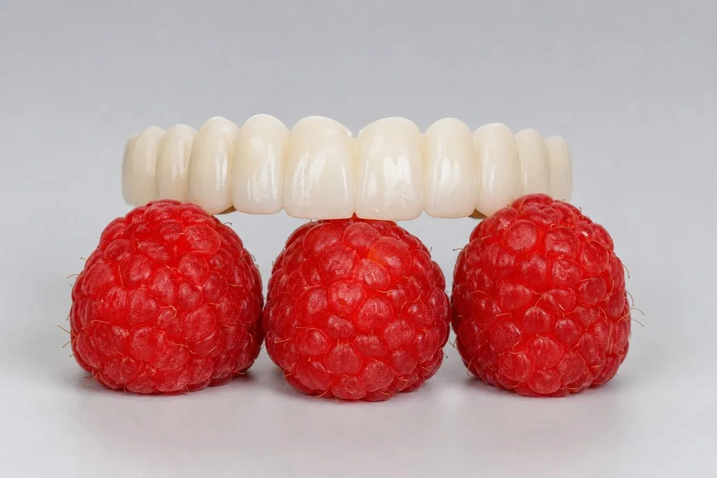 Vollkeramische Zahnbrücke neben frischen Himbeeren